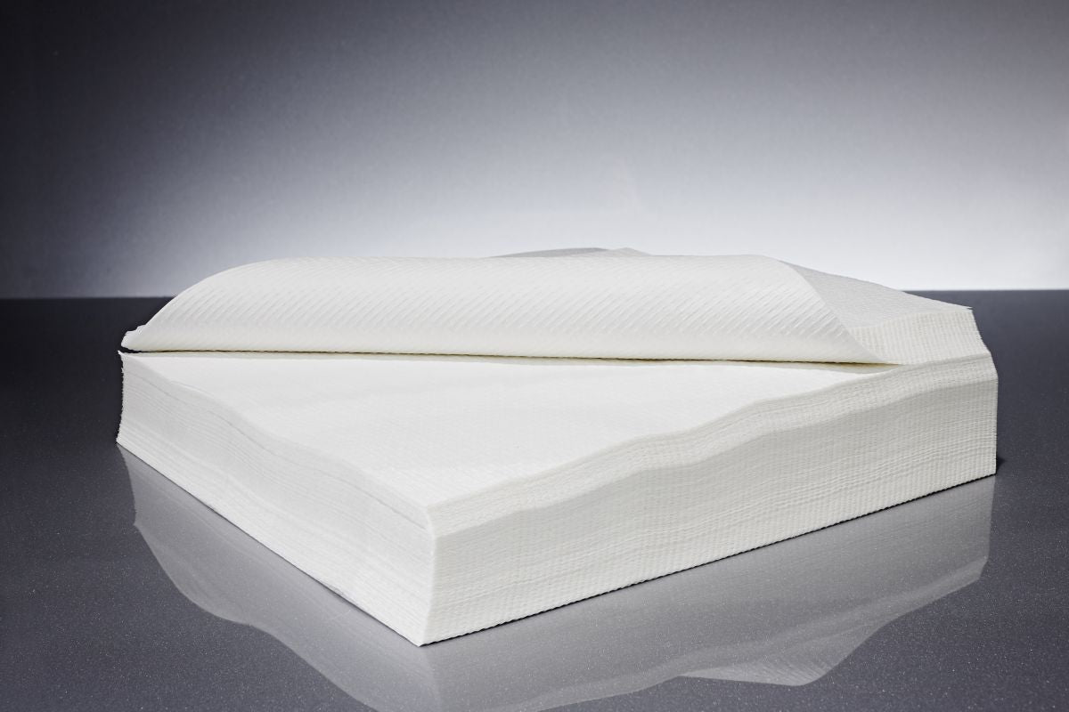 Hochwertige weiße Kreppservietten für den medizinischen Gebrauch auf grauem Hintergrund.