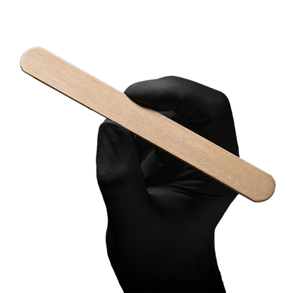 Schwarzer Handschuh hält einen splitterfreien Holzmundspatel mit abgerundeten Kanten.