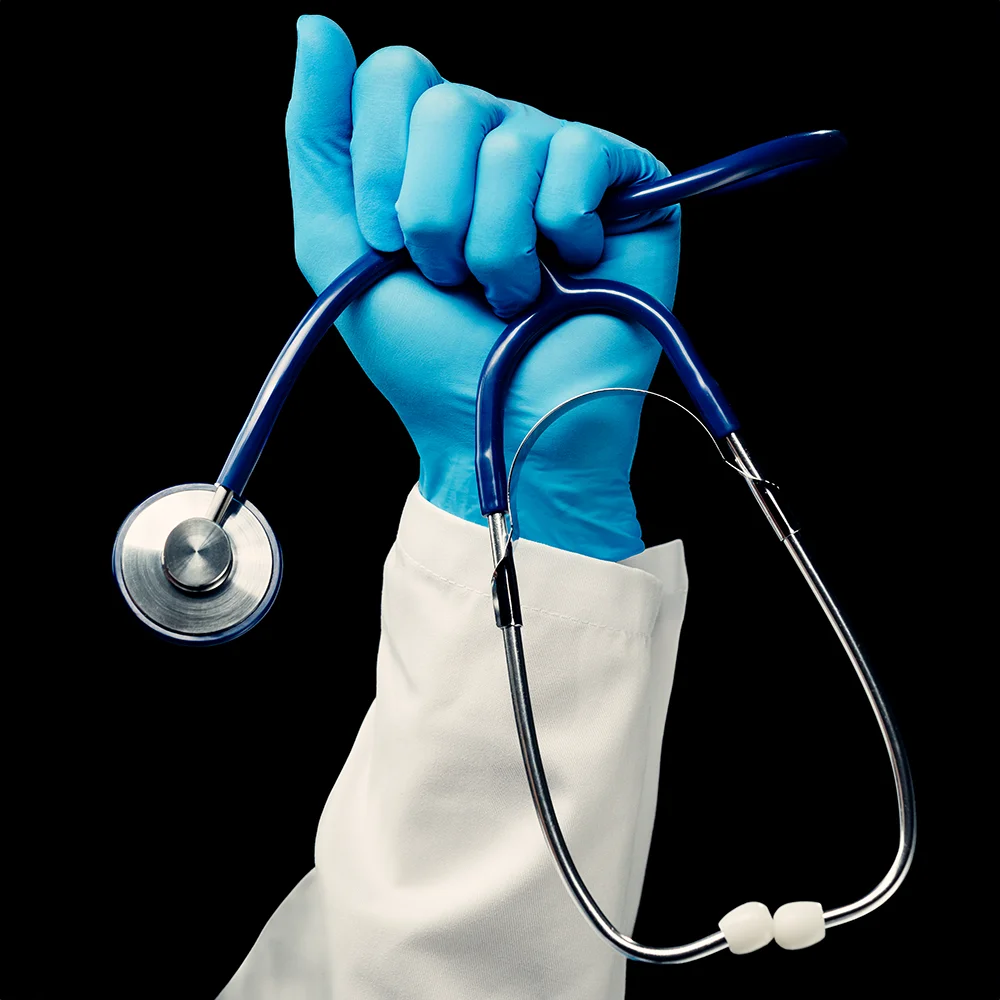 Medizinisches Stethoskop in blauer Handschuhhand auf schwarzem Hintergrund.