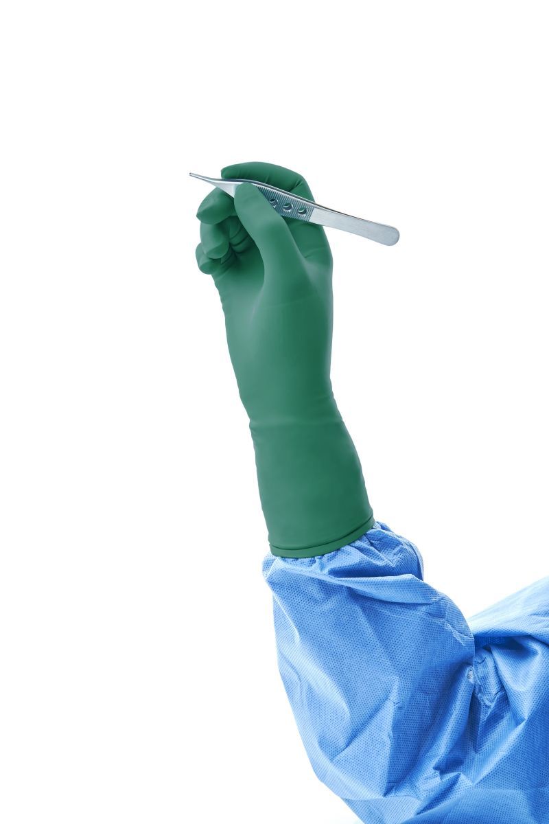 Grüner Gammex Non-Latex Handschuh hält chirurgisches Instrument.