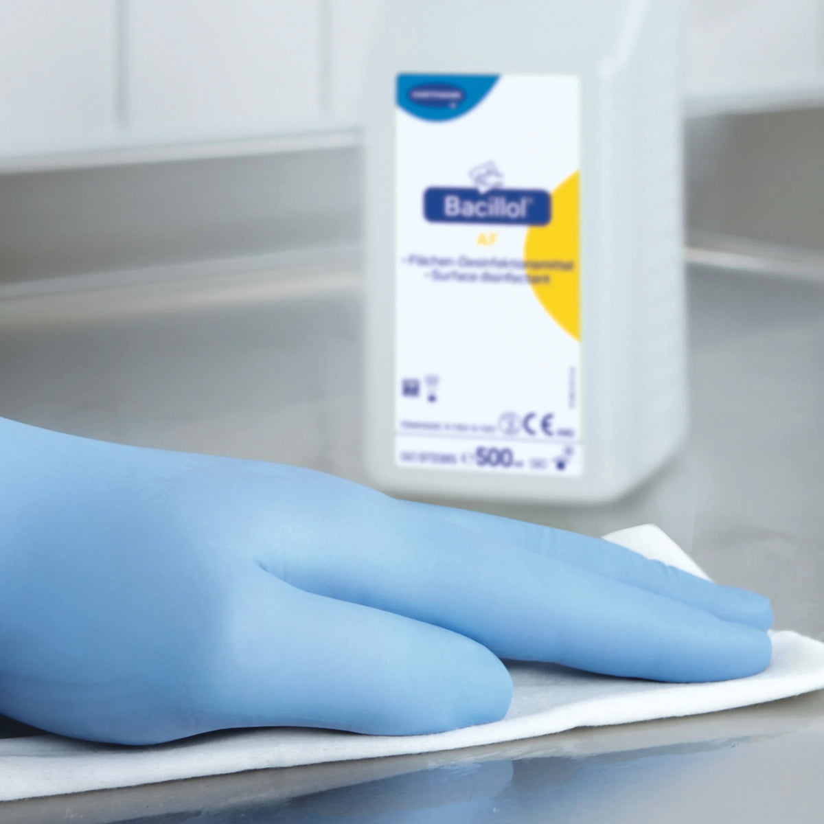 Blaue behandschuhte Hand wischt mit Bacillol AF desinfizierte Oberfläche.