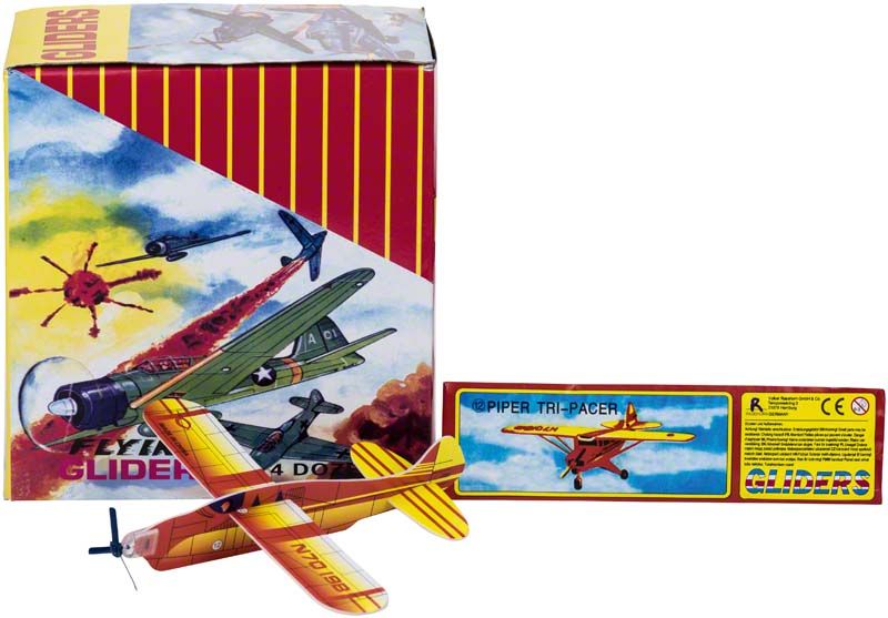 Styroporflieger mit Propeller vor bunter Verpackung mit Flugzeugmotiven.
