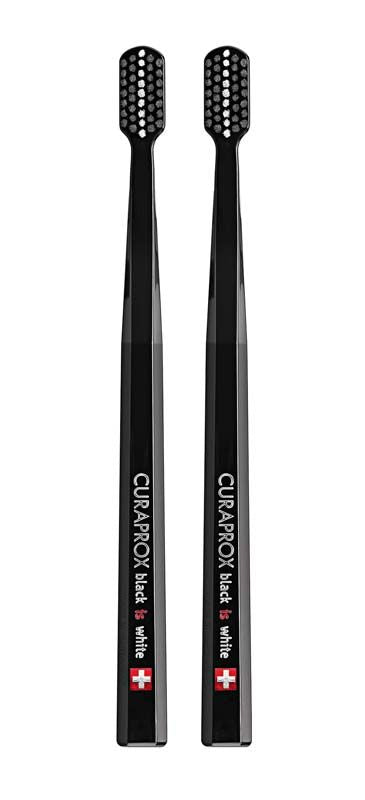 Zwei schwarze CURAPROX Black is Black Zahnbürsten mit weißen Borsten.