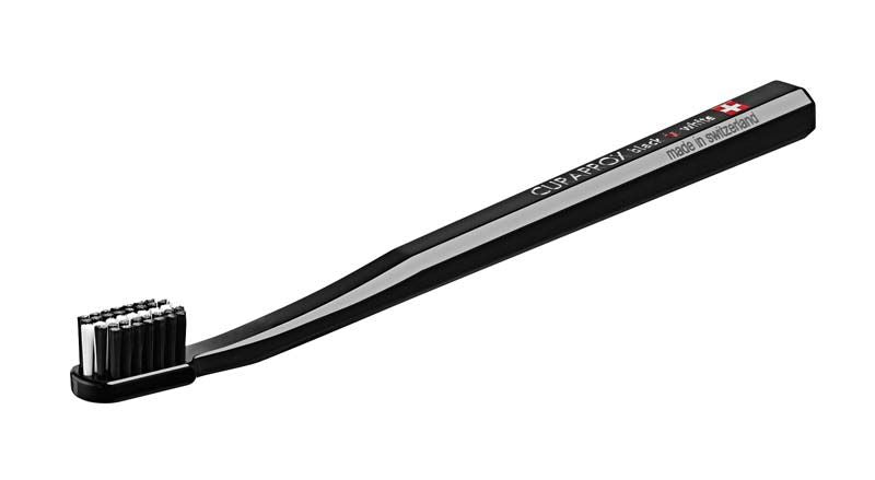 Schwarze CURAPROX Zahnbürste mit weißen Borsten und Schweizer Flagge auf dem Griff.