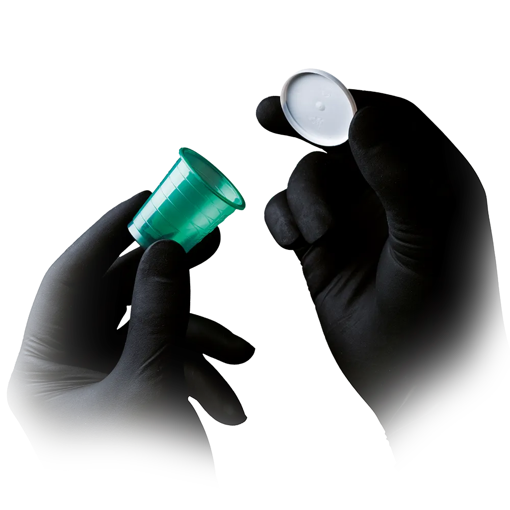 Schwarze Latexhandschuhe Style Black, die einen grünen Kunststoffbecher halten.