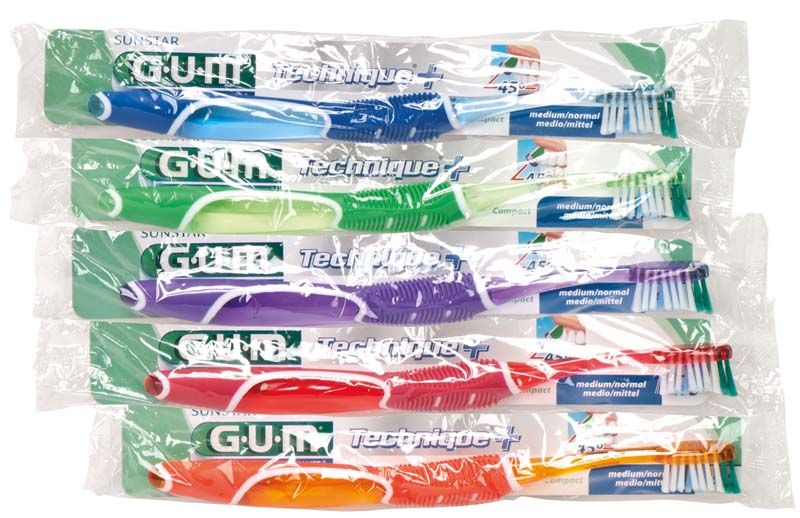 Sechs verpackte GUM® Technique® + Zahnbürsten in verschiedenen Farben.