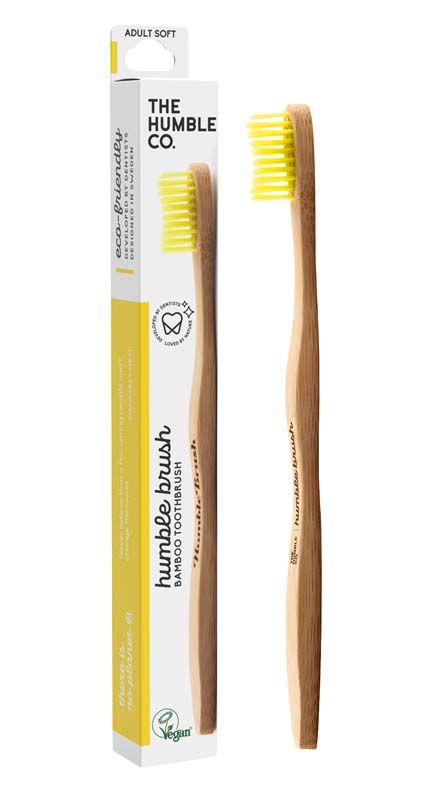 Humble Brush Zahnbürste mit gelben Borsten und Verpackung im Hintergrund.