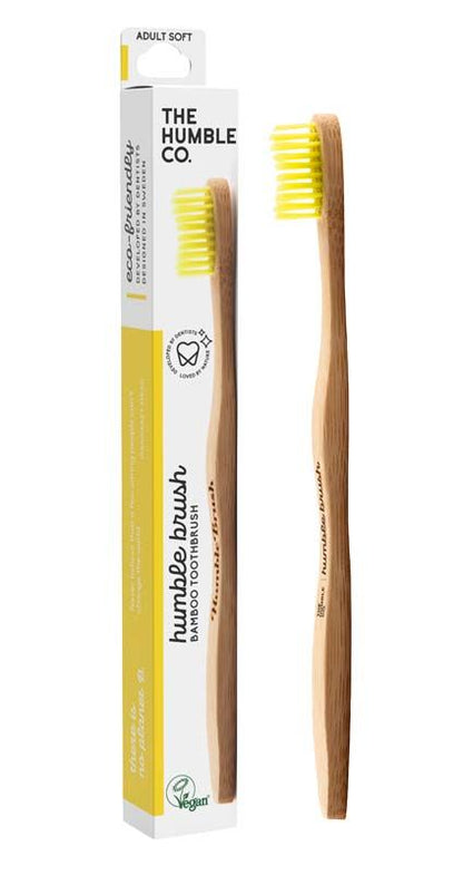 Humble Brush Zahnbürste mit gelben Borsten und Verpackung im Hintergrund.