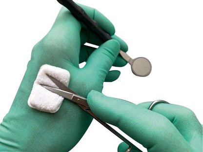 Selbstklebendes Reinigungspad auf grünem Handschuh mit Dentalinstrumenten.