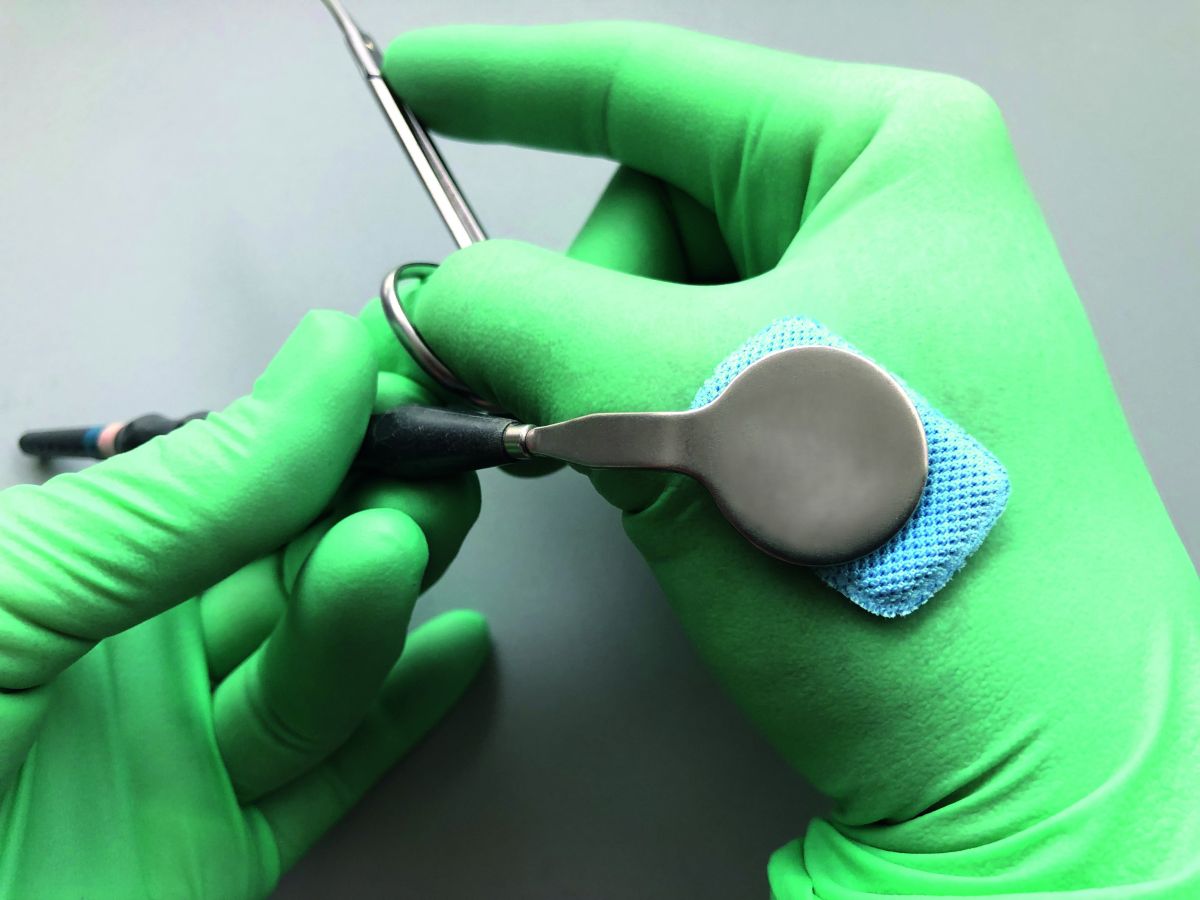 Grünes Handschuhpad mit blauem Fit-N-Swipe Trocknungspad auf dentalem Mundspiegel.