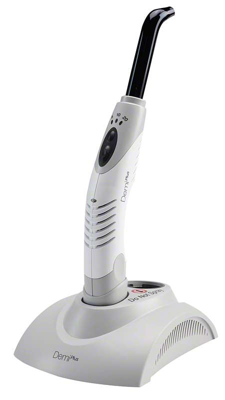 Demi™ Plus Polymersiationslampe mit ergonomischem Griff auf Ladestation.