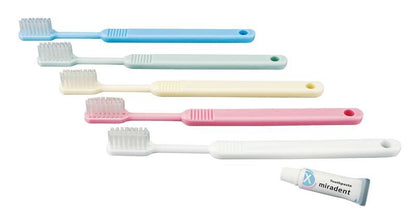 Fünf Einwegzahnbürsten in verschiedenen Farben mit Tube miradent Zahnpasta.