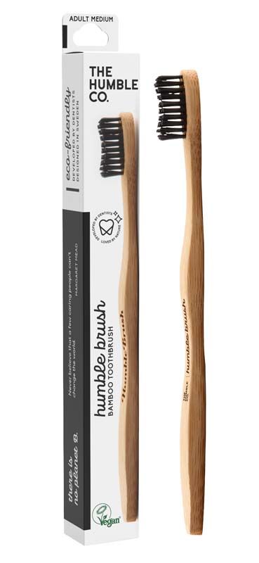 Humble Brush Zahnbürste mit Bambusgriff und schwarzen Borsten neben Verpackung.