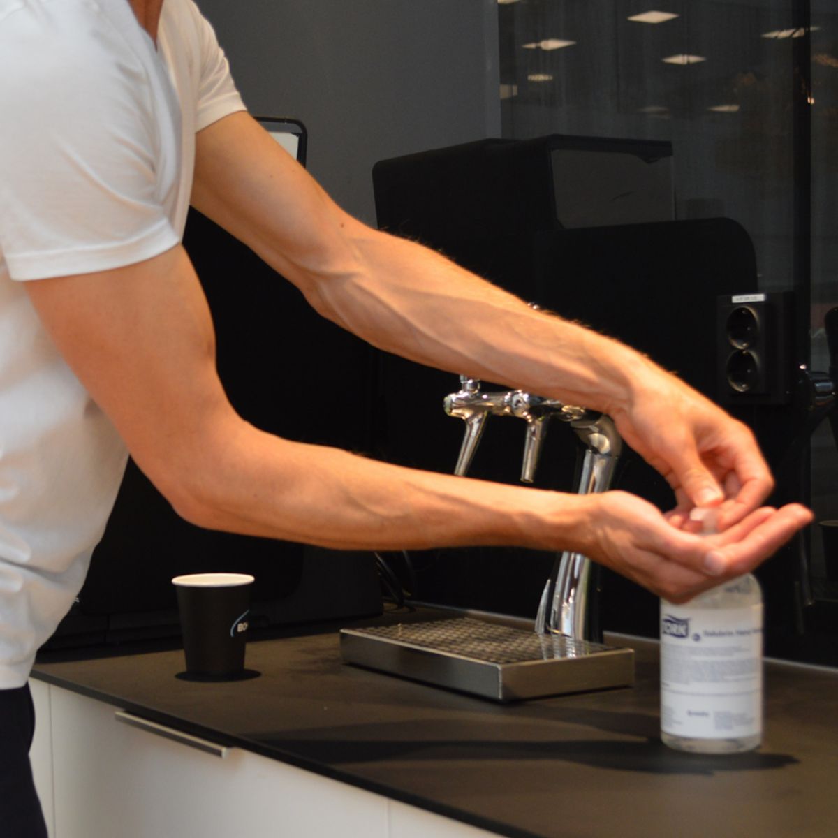 Mann verwendet Tork Salubrin Händedesinfektionsgel 500ml neben Waschbecken.