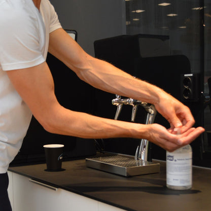 Mann verwendet Tork Salubrin Händedesinfektionsgel 500ml neben Waschbecken.