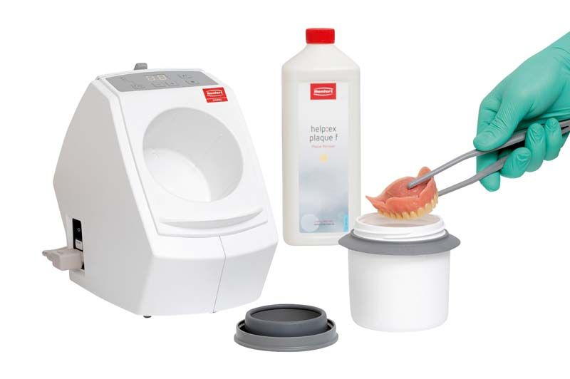 SYMPRO Prothesenreinigungsgerät mit Reinigungsflüssigkeit und Zahnersatz im Einsatz.