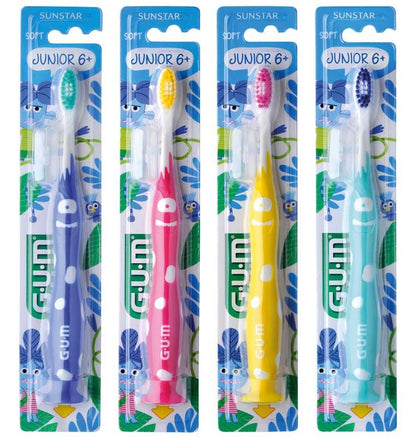 Vier GUM® JUNIOR Zahnbürsten in Blau, Rot, Gelb, Grün mit Gesichtsmustern und Hygienekappen.