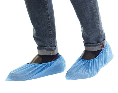 Hellblaue wasserfeste Kunststoff-Überschuhe mit Gummizug an Schuhen getragen.