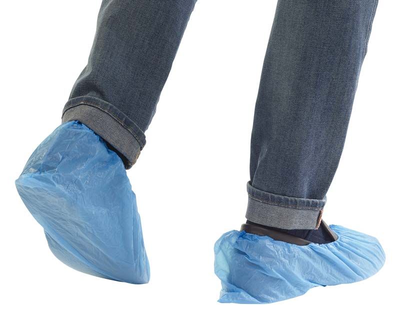 Hellblaue Kunststoff-Überschuhe mit Gummizug an getragenen Jeans.