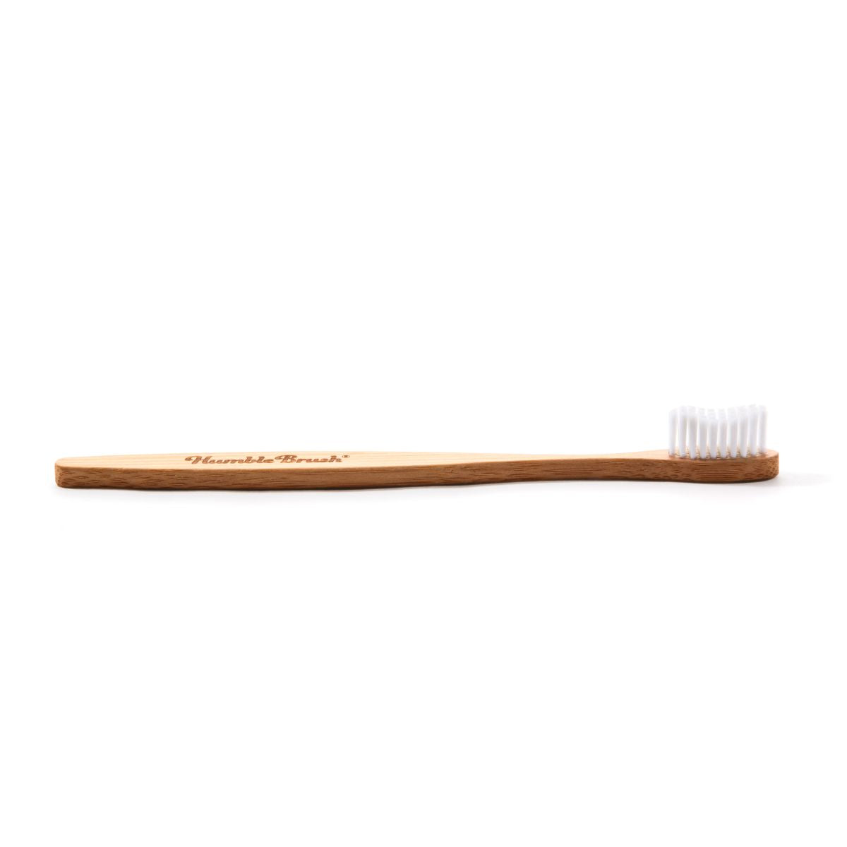 Humble Brush Zahnbürste mit Bambusgriff und weißen, weichen Borsten seitlich.