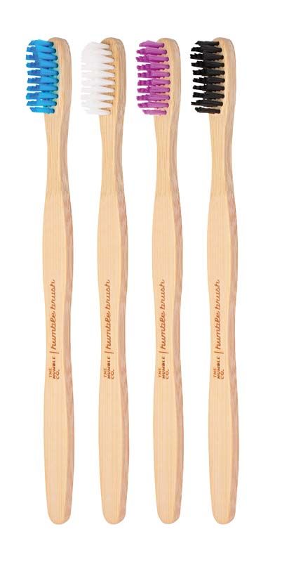 Vier Humble Brush Zahnbürsten mit bunten Borsten und Holzgriff.