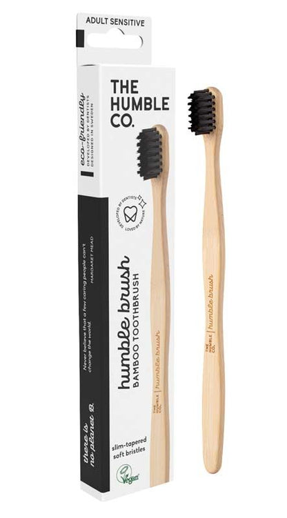 Schwarze Humble Brush Zahnbürste mit Bambusgriff neben Verpackung.