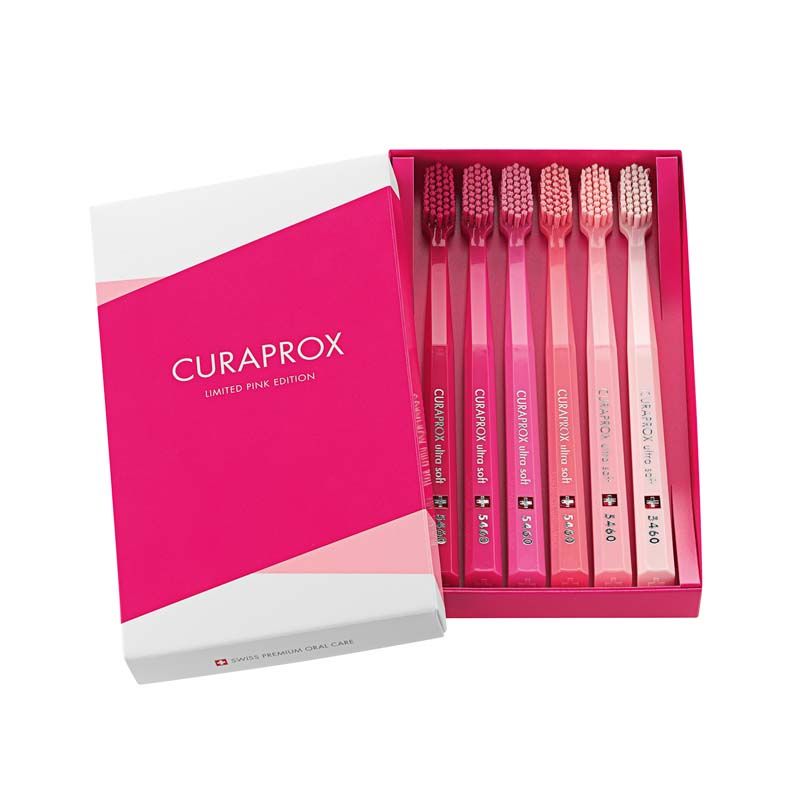 Sechs CURAPROX Zahnbürsten CS 5460 in pinken Farbtönen in geöffneter Verpackung.