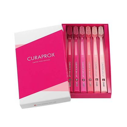 Sechs CURAPROX Zahnbürsten CS 5460 in pinken Farbtönen in geöffneter Verpackung.