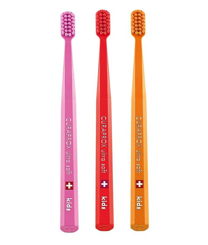 Drei CURAPROX Kinderzahnbürsten CS ultra soft in Pink, Rot und Orange.