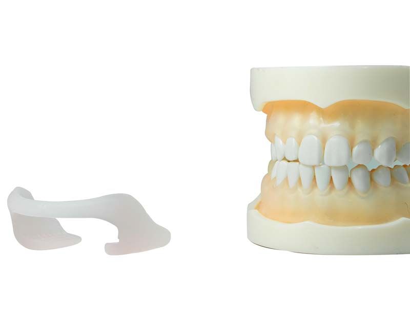 Temporäre Aufbissschiene RehaSplint soft neben Zahnmodell.