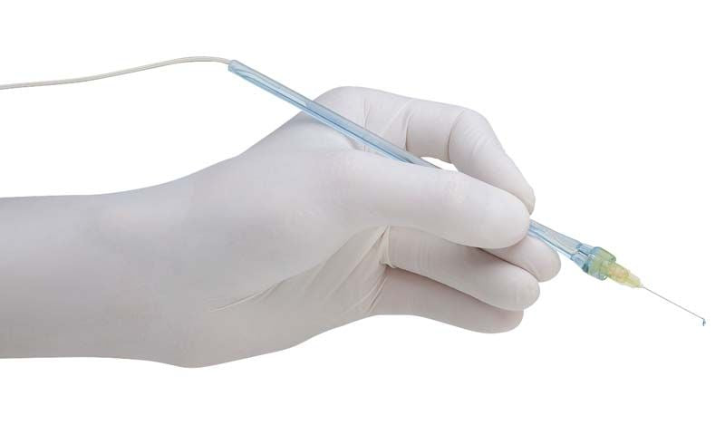 Handstück mit blauer 27G-Kanüle, gehalten von behandschuhter Hand.