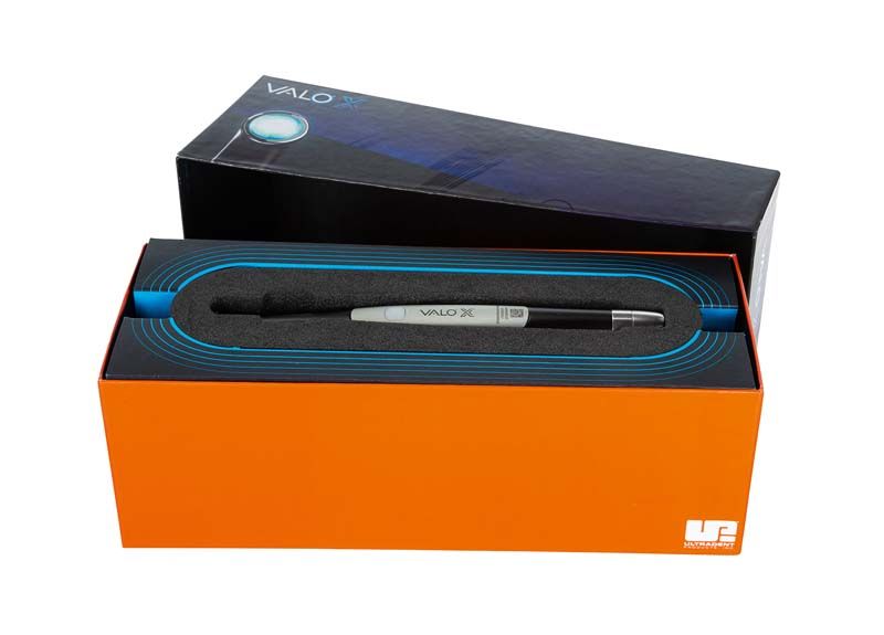 VALO™ X Polymerisationslampe in geöffneter Verpackung mit Sicht auf Aluminiumkörper.