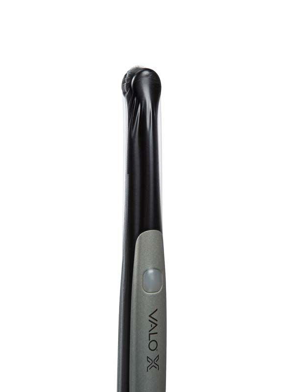 VALO™ X Polymerisationslampe mit aufgesetzter Hygieneschutzhülle im Vordergrund.