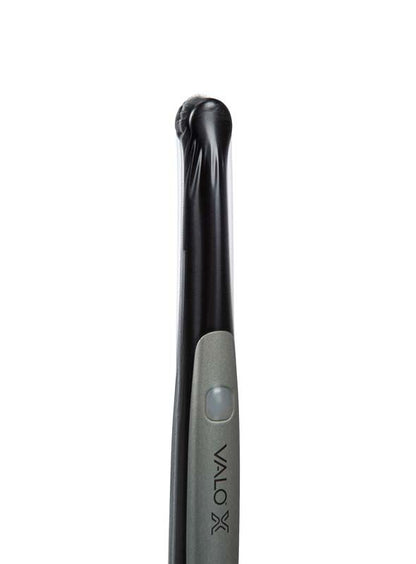 VALO™ X Polymerisationslampe mit aufgesetzter Hygieneschutzhülle im Vordergrund.
