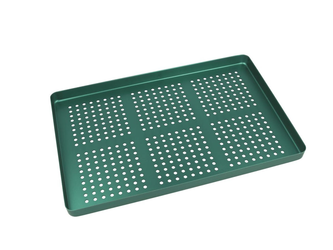 Grünes gelochtes Aluminiumtray zur Organisation von Dentalinstrumenten.