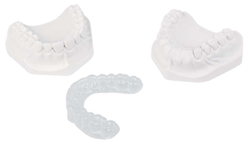 Drei zahnmedizinische Modelle und eine transparente Bleichschiene aus COPYPLAST®-Tiefziehfolie.