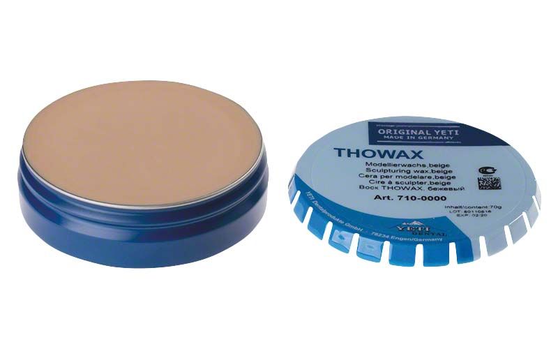 Thowax Modellierwachs beige in geöffneter blauer Dose neben geschlossenem Deckel.