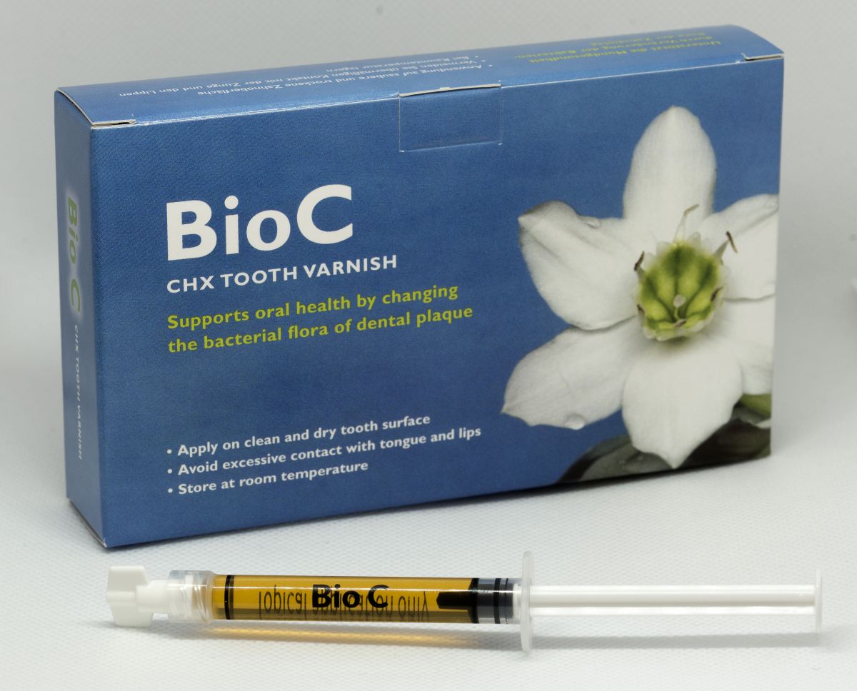 EC40 CHX-Zahnlack-Spritze vor Verpackung mit weißer Blume.