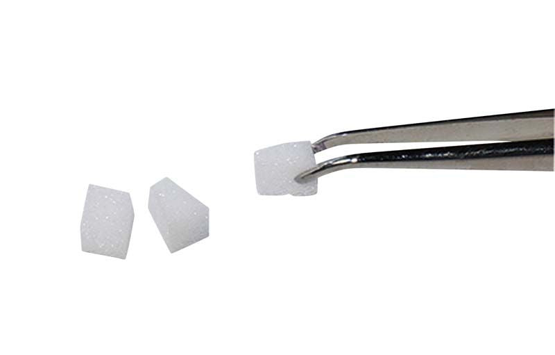 Spezial-Schaumstoffpellets von Erkodent, einzeln mit Pinzette gehalten.