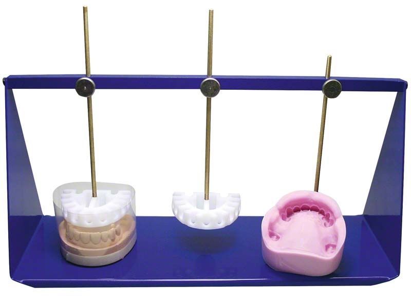 Fixiervorrichtung mit drei Zahnersatzmodellen auf blauer Halterung.