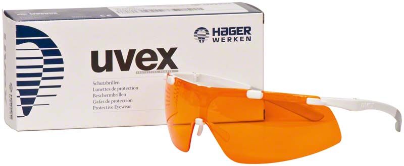 Schutzbrille mit orangefarbenen Gläsern und weißem Gestell vor Verpackung.
