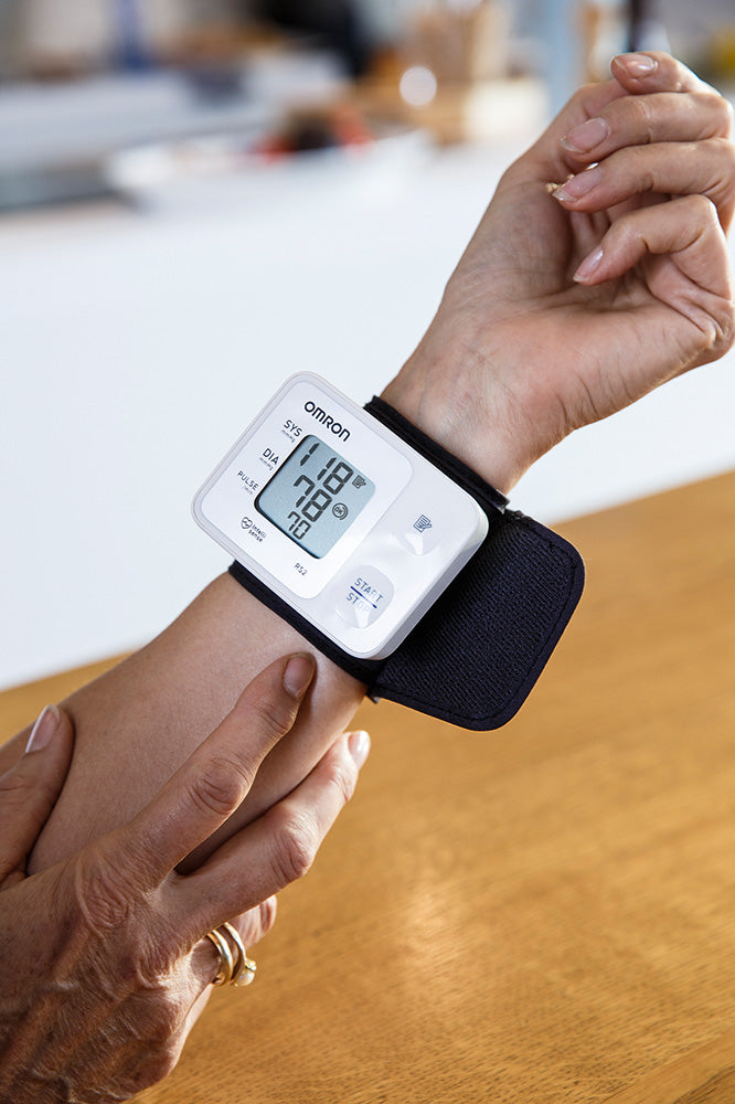 Omron RS2 Handgelenk-Blutdruckmessgerät am Handgelenk, zeigt Messwerte auf LCD-Display.