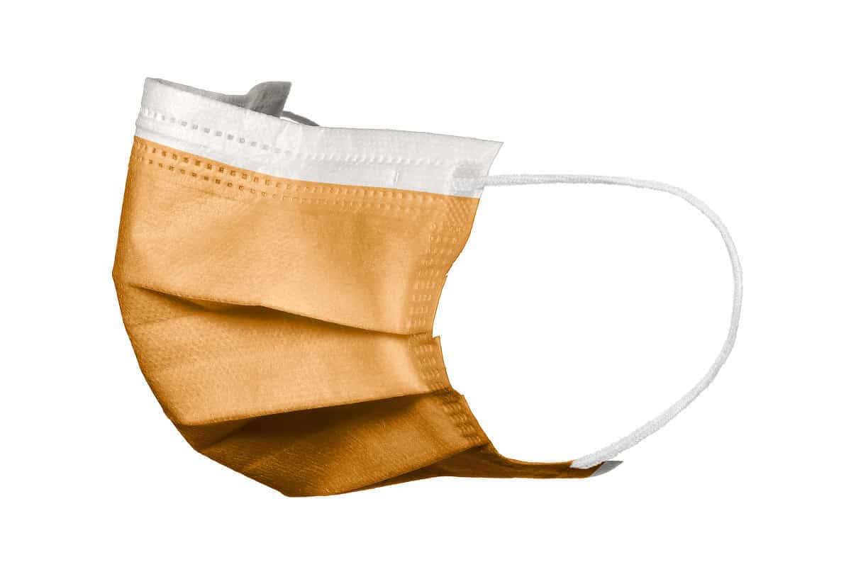 Orangefarbener 3-lagiger Mundschutz mit elastischen Bändern und Nasenbügel.