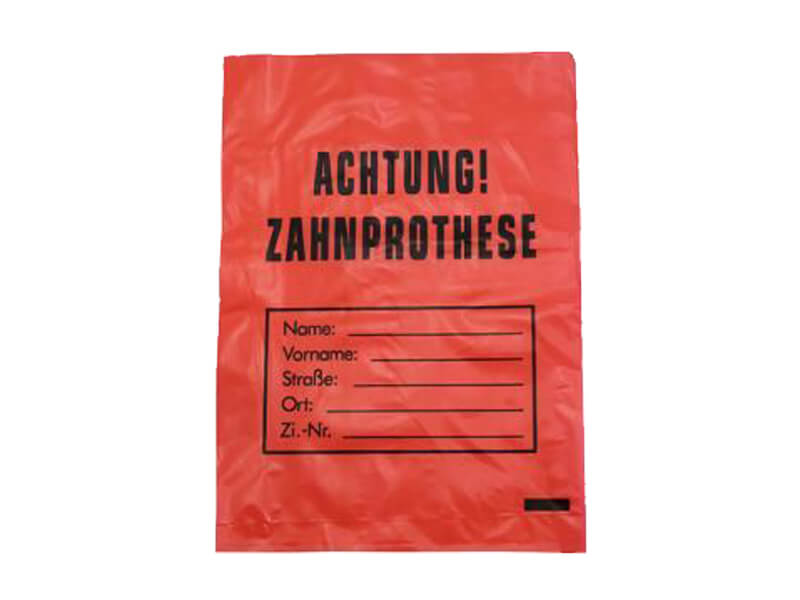 Roter Zahnprothesenbeutel mit Aufschrift "Achtung! Zahnprothese" und Beschriftungsfeldern.