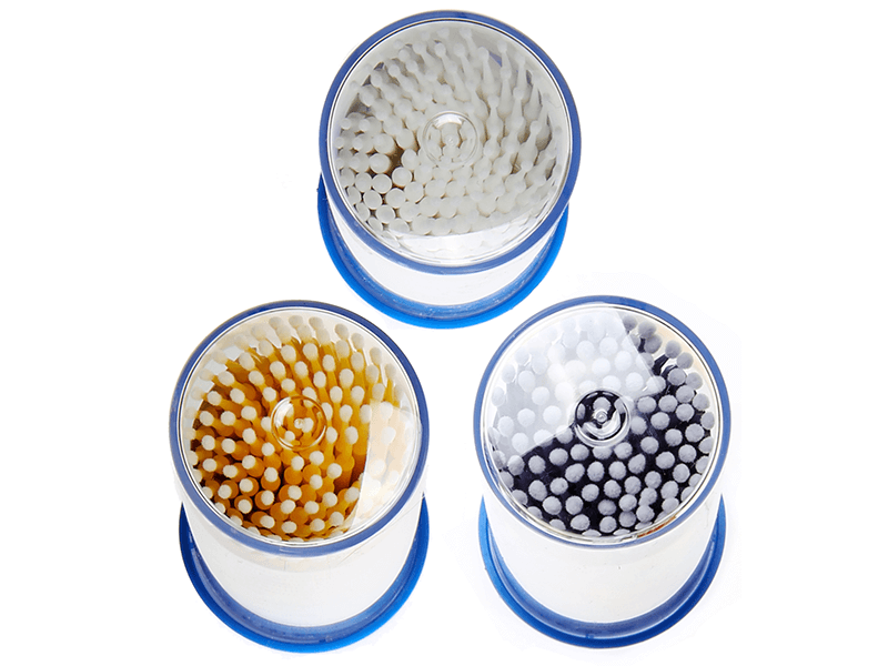 Applikatoren in drei Farben (Weiß, Gelb, Schwarz) in runden Plastikboxen.