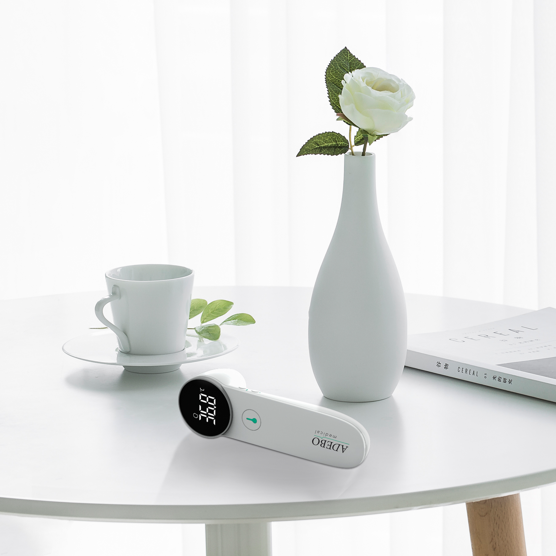 Berührungsloses 2-in-1-Fieberthermometer auf Tisch neben weißer Vase.