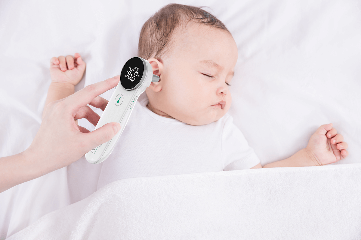 Berührungsloses Fieberthermometer bei Messung der Ohrtemperatur eines schlafenden Babys.